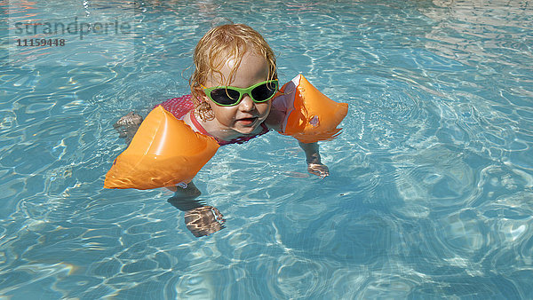 Kleines Mädchen mit Schwimmflügel im Schwimmbad