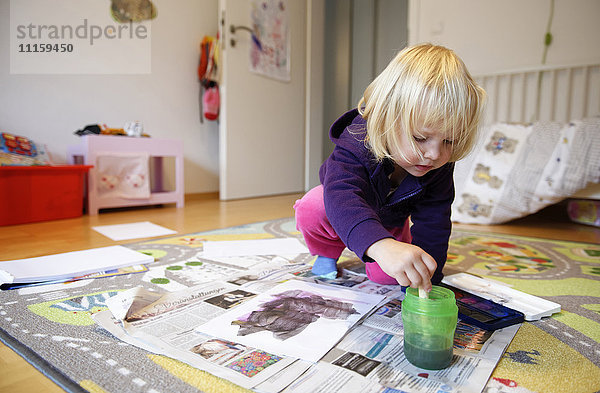 Kleine Mädchen malen mit Aquarellen auf dem Boden des Kinderzimmers