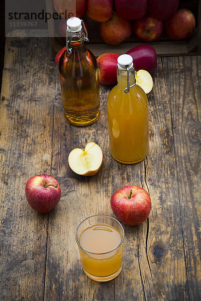 Flasche und Glas Apfelsaft  trüb und klar  rote Äpfel auf Holz