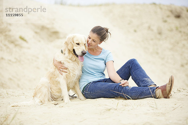 Junge Frau mit Hund im Sand