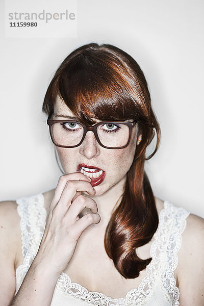 Porträt einer Frau mit Brille und Hand im Mund