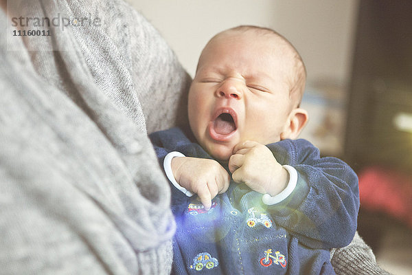 Müde Baby in den Armen der Mutter