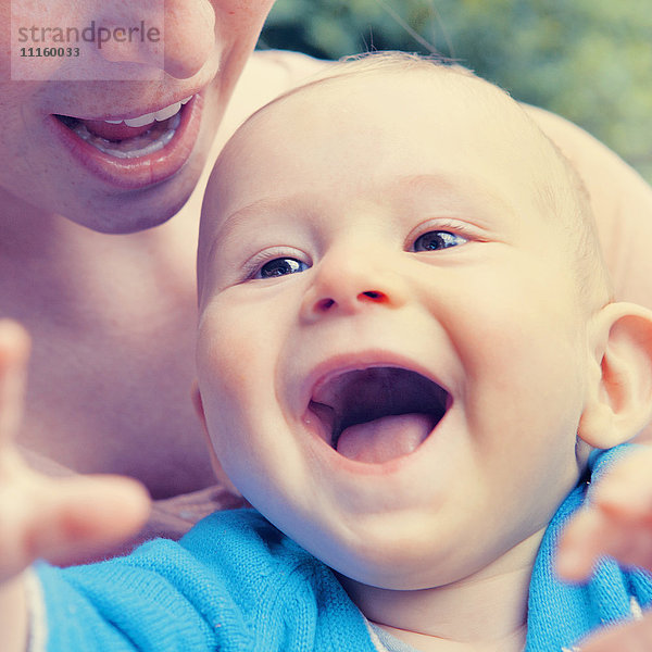 Glückliches Baby in den Armen der Mutter