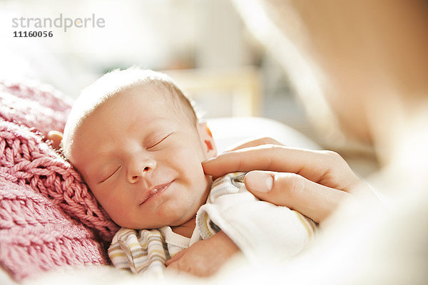 Schlafende Neugeborene  die von einer Hand berührt werden.