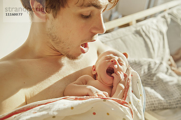 Vater imitiert Gähnen seines Neugeborenen