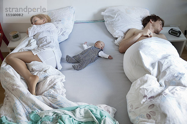 Eltern schlafen mit Neugeborenen im Bett