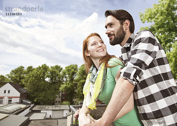 Lächelndes junges Paar auf dem Balkon in der Stadt