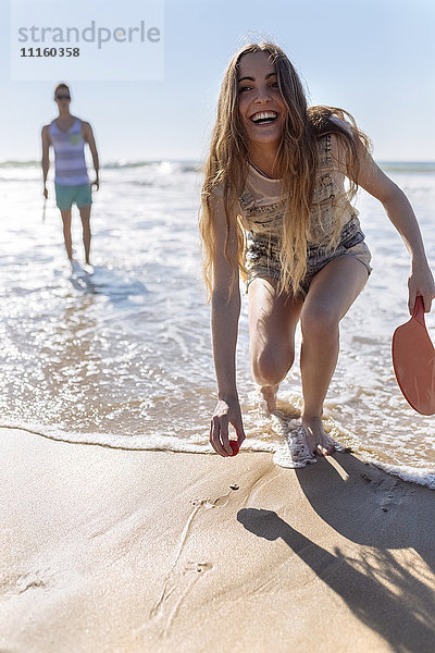 Lachendes Teenagermädchen beim Strandpaddeln am Strand