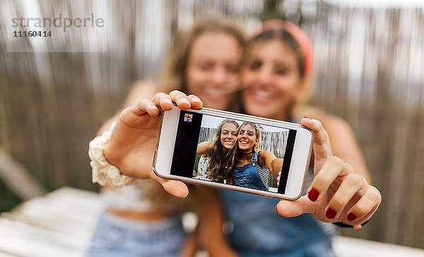 Selfie von zwei lächelnden Teenager-Mädchen auf dem Display des Smartphones