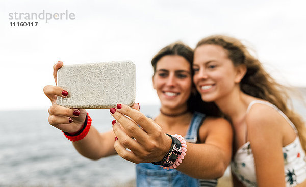 Zwei beste Freunde nehmen Selfie mit Smartphone an der Küste  Nahaufnahme