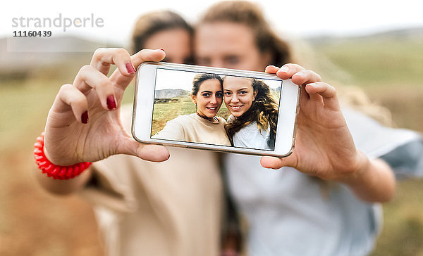 Selfie von zwei lächelnden Teenager-Mädchen auf dem Display des Smartphones