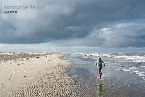 Dänemark  Skagen  Junge in Winterkleidung am Strand unterwegs