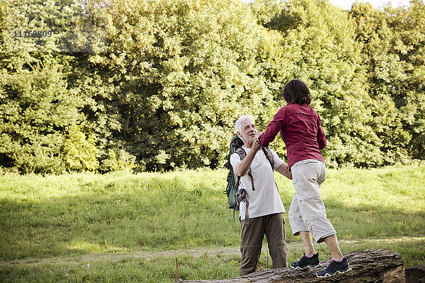 Seniorenpaar auf einer Wanderung auf Baumstamm balancierend