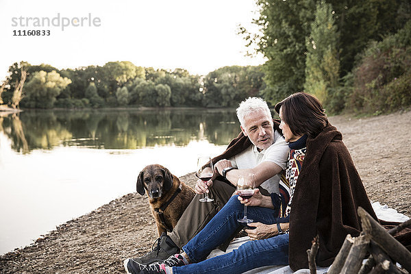 Seniorenpaar mit Hund am See am Abend