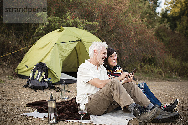 Glückliches Seniorenpaar mit Handy im Zelt