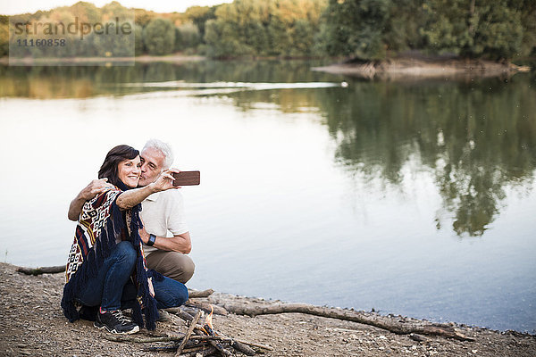 Seniorenpaar am See mit einem Selfie
