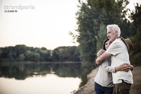 Seniorenpaar umarmt an einem See