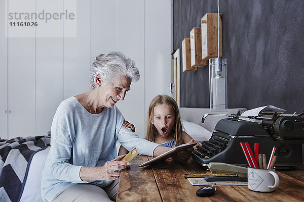Großmutter und verblüffte Enkelin beim Online-Shopping zu Hause