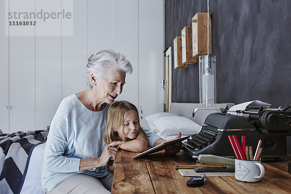 Großmutter und Enkelin beim Betrachten der Tablette zu Hause