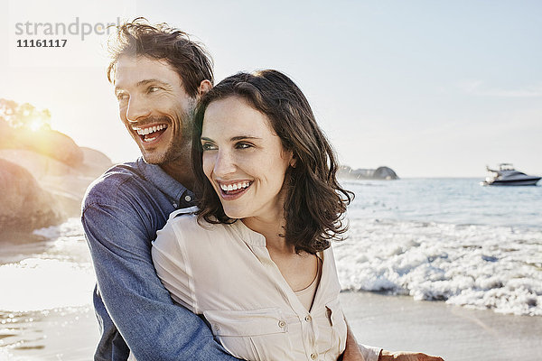 Ein glückliches Paar umarmt sich am Strand.