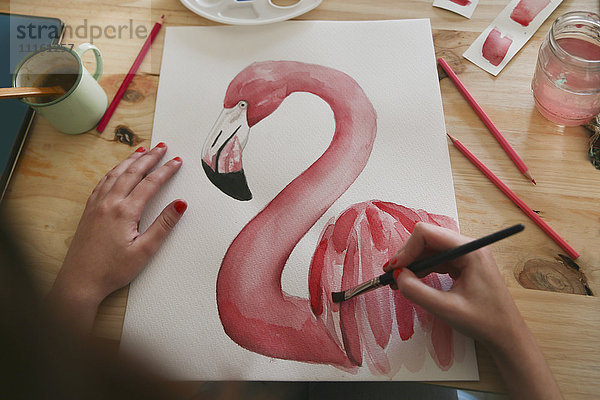 Damenhandmalerei Aquarell eines Flamingos auf dem Schreibtisch im Atelier