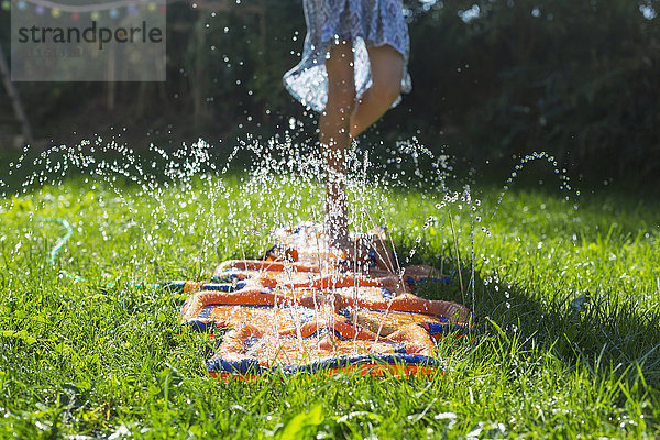Mädchen springen auf auf aufblasbarem Wasserkissen im Garten  Teilansicht