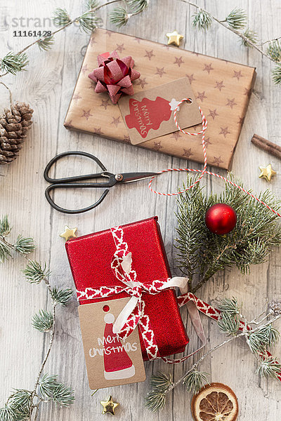 Weihnachtsschmuck  Scheren und verpackte Geschenke auf Holz