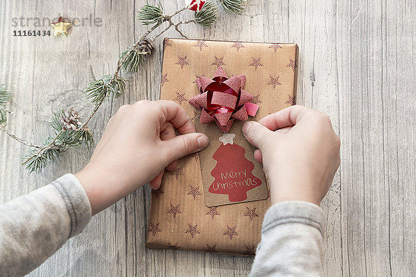 Hände des Mädchens verpacken Weihnachtsgeschenk
