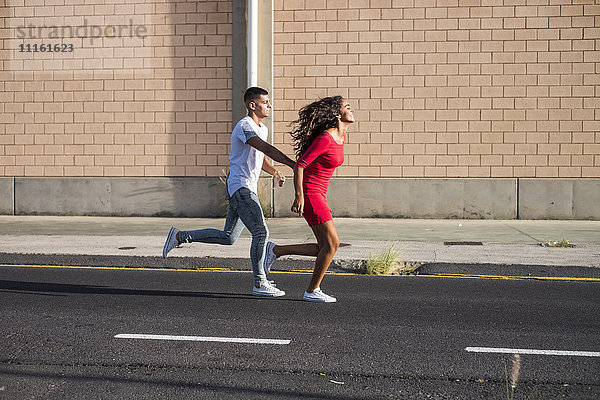 Teenager-Paar läuft Hand in Hand auf einer Straße