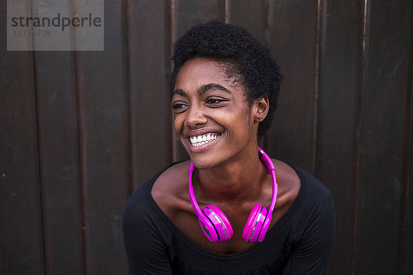 Porträt der lachenden Frau mit rosa Kopfhörern