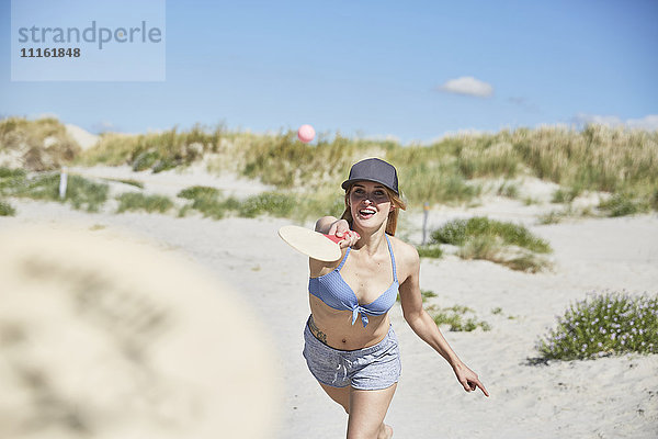 Fröhliche junge Frau am Strand beim Strandpaddeln