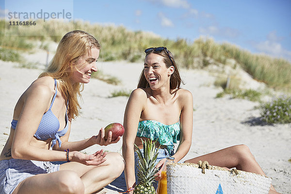 Zwei Freundinnen am Strand bei einem gesunden Snack