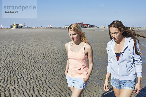 Zwei Freundinnen  die am Strand spazieren gehen.