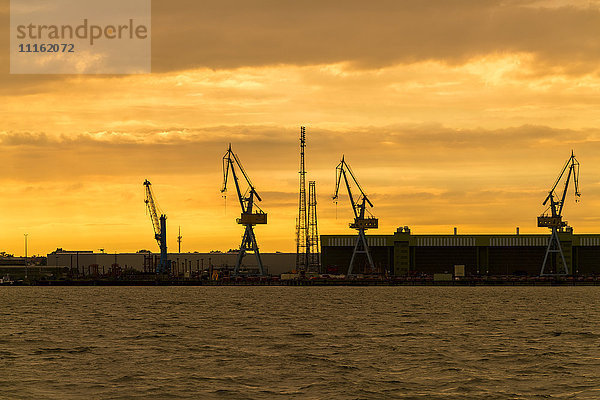 Deutschland  Stralsund  Blick auf Silhouetten von Hafenkranen auf der Werft bei Dämmerung