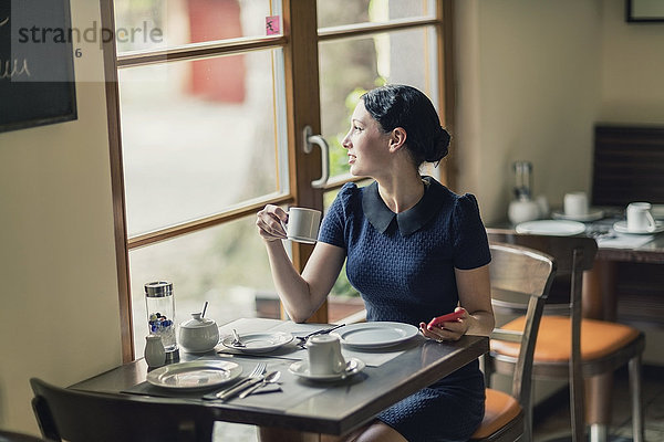 Junge Frau in einem Café mit Blick aus dem Fenster