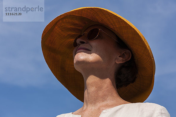 Lächelnde Frau mit Sommerhut und Sonnenbrille