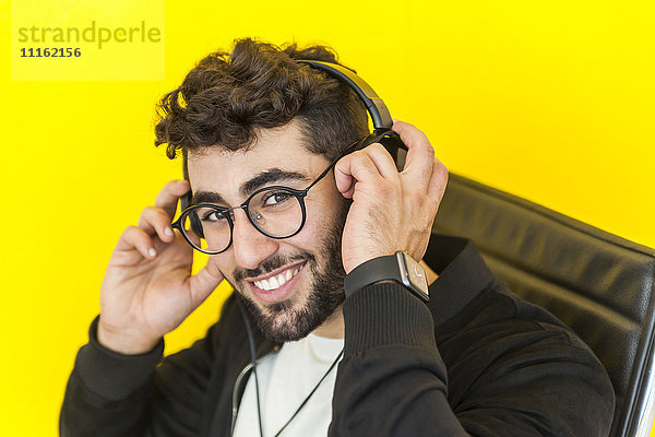 Porträt eines lächelnden Mannes mit Brille auf dem Kopfhörer
