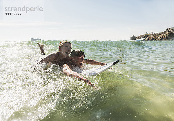 Zwei Freunde haben Spaß auf dem Surfbrett im Meer