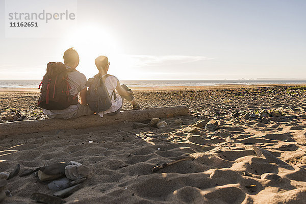 Frankreich  Bretagne  Finistere  Halbinsel Crozon  Paar beim Strandspaziergang  am Strand sitzen  Sonnenuntergang genießen