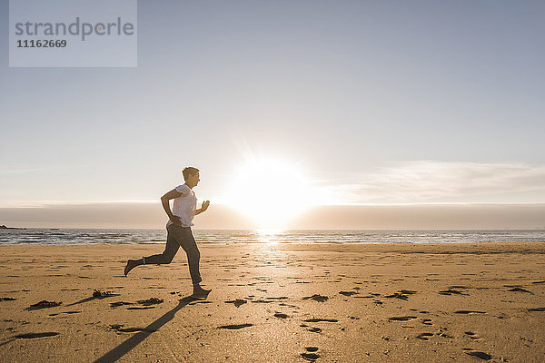 Frankreich  Bretagne  Halbinsel Crozon  Frau läuft am Strand bei Sonnenuntergang