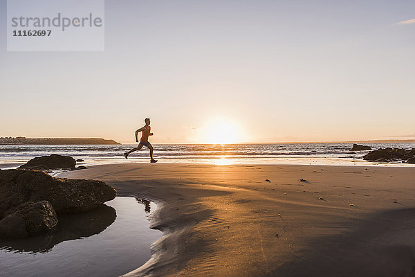 Frankreich  Halbinsel Crozon  Jogger am Strand bei Sonnenuntergang