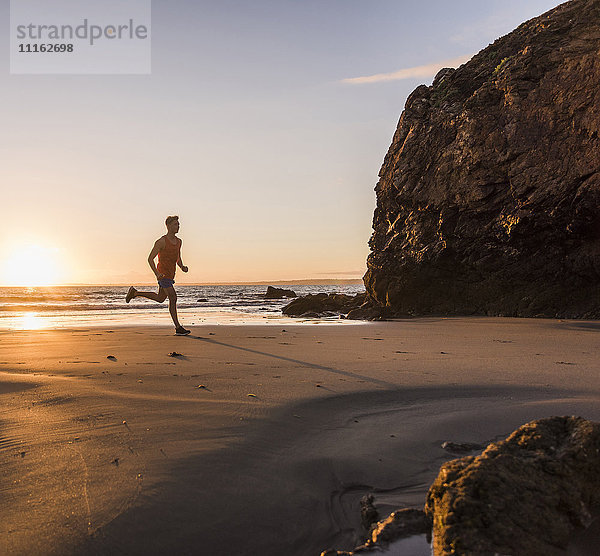 Frankreich  Halbinsel Crozon  Jogger am Strand bei Sonnenuntergang