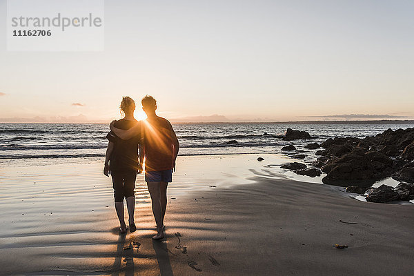 Frankreich  Halbinsel Corzon  Paar beim Sonnenuntergang am Strand spazieren gehen