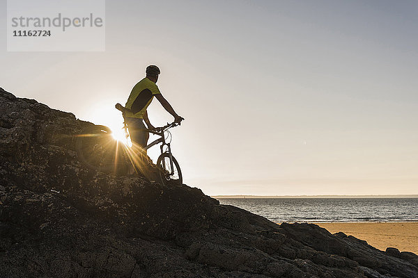 Frankreich  Halbinsel Crozon  Mountainbiker beim Sonnenuntergang