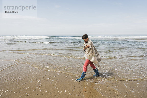 Reife Frau  die am Strand spazieren geht.