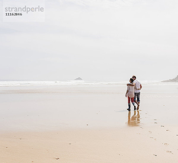 Ein reifes Paar  das am Strand spazieren geht.