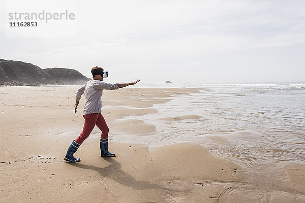Reife Frau am Strand mit VR-Brille