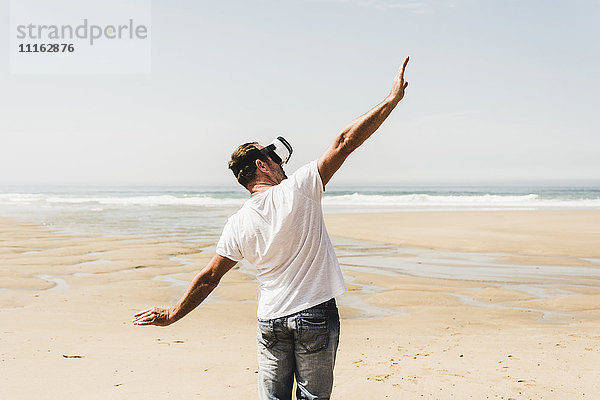 Erwachsener Mann am Strand stehend mit VR-Brille