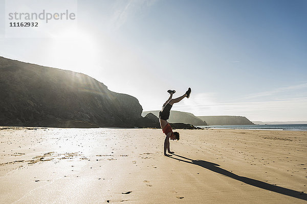 Frankreich  Halbinsel Crozon  junger Mann beim Handstand am Strand