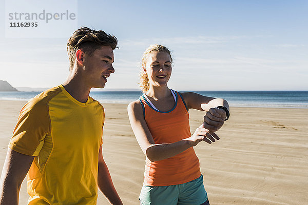 Frankreich  Halbinsel Crozon  sportliches junges Paar am Strand mit Blick auf die Uhr